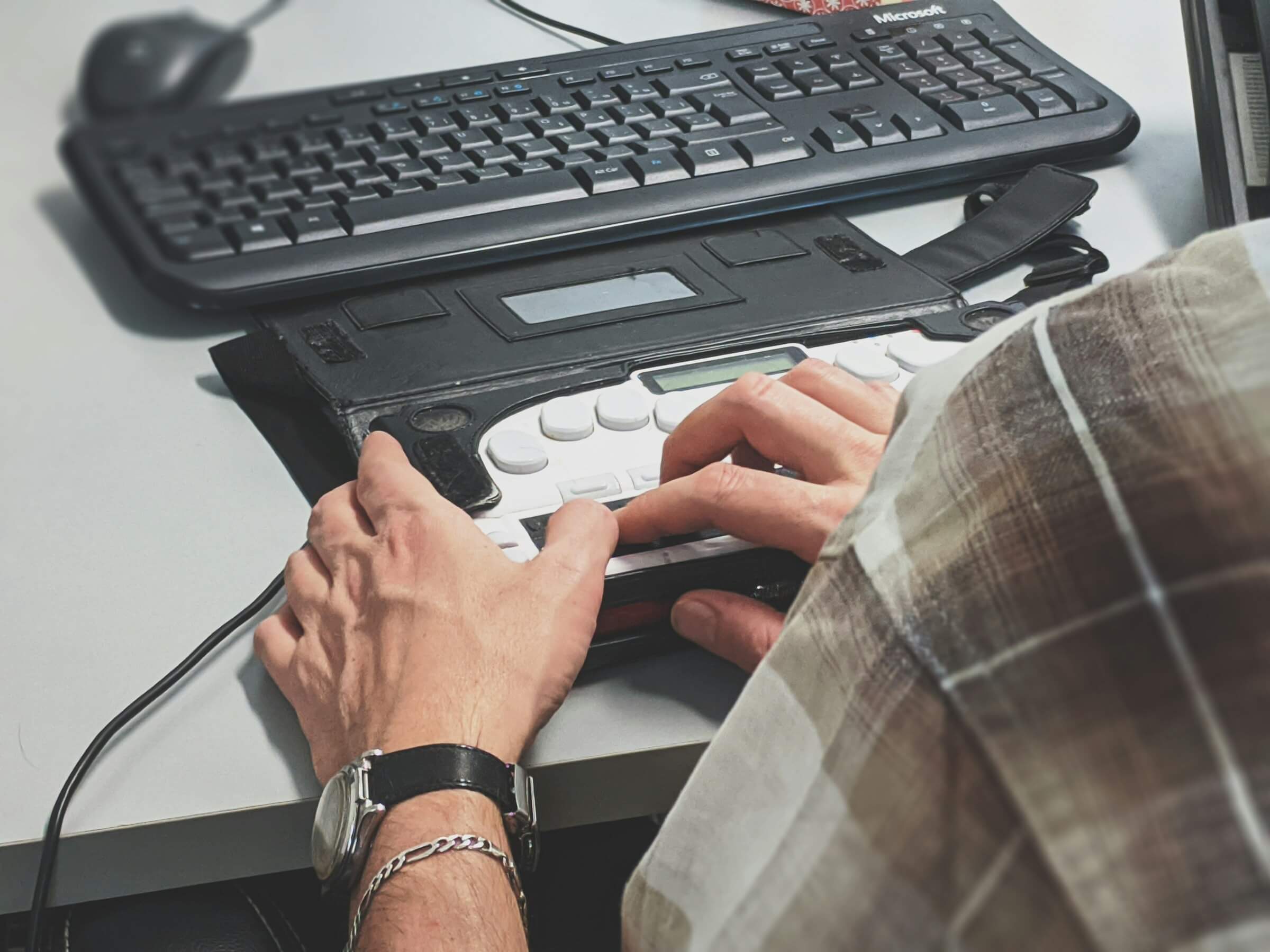 Photo of person using a computer keyboard with assistive device.